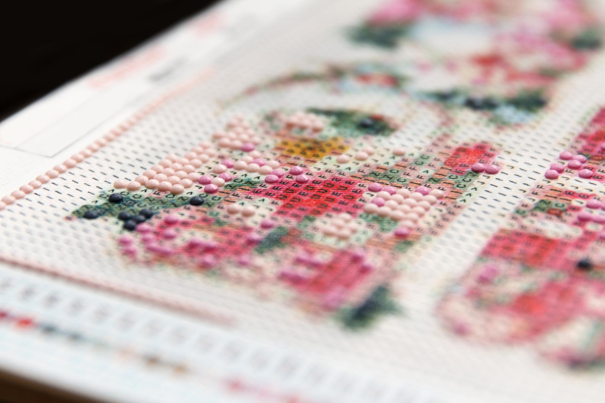 Detailaufnahme feiner Kreuzstiche in Pastellfarben